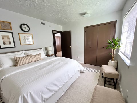 A bedroom with a large bed and a brown wardrobe.