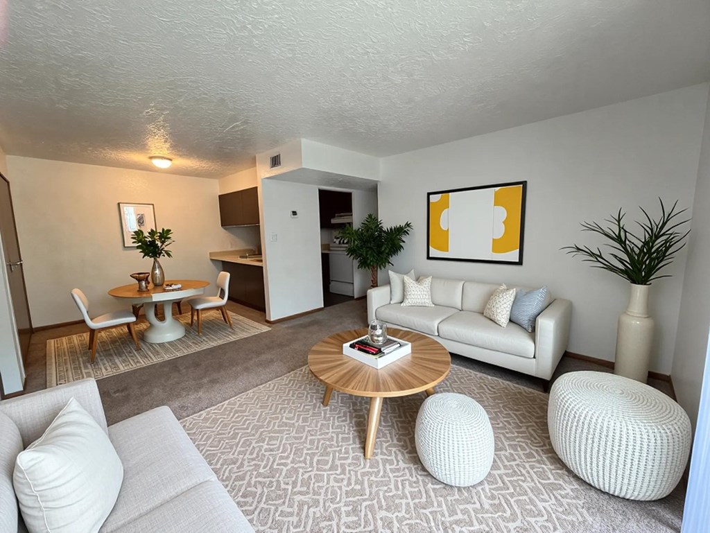 A living room with a white couch, a wooden coffee table, and a painting on the wall.