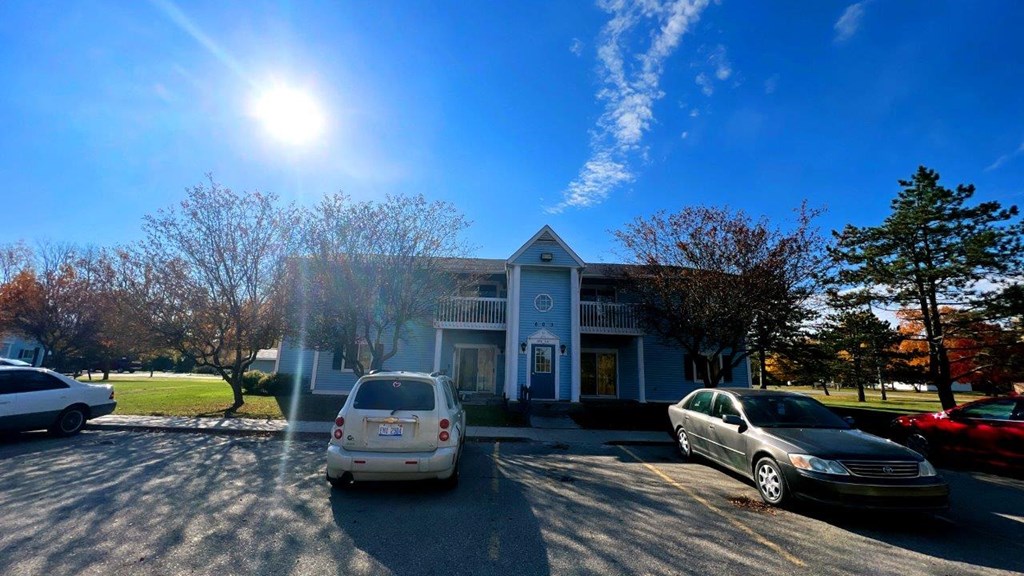a parking lot with cars in front of a blue house