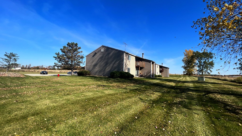 a barn with a green lawn and a blue sky