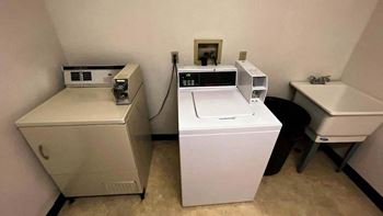 A room with a washing machine, dryer, and ironing board.