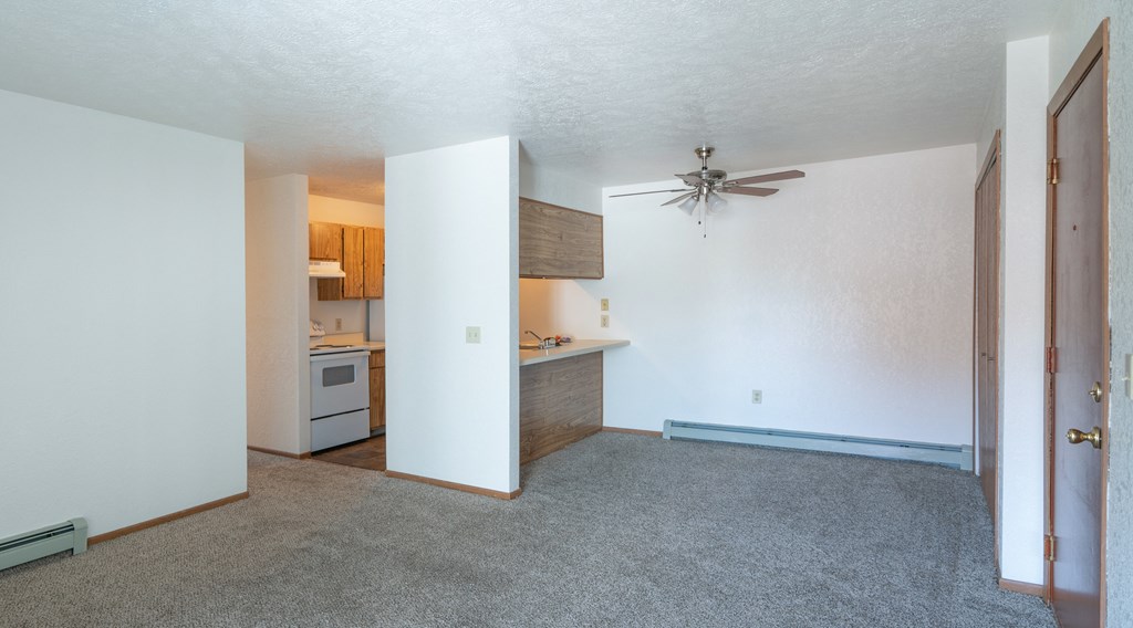an empty living room and kitchen with a ceiling fan