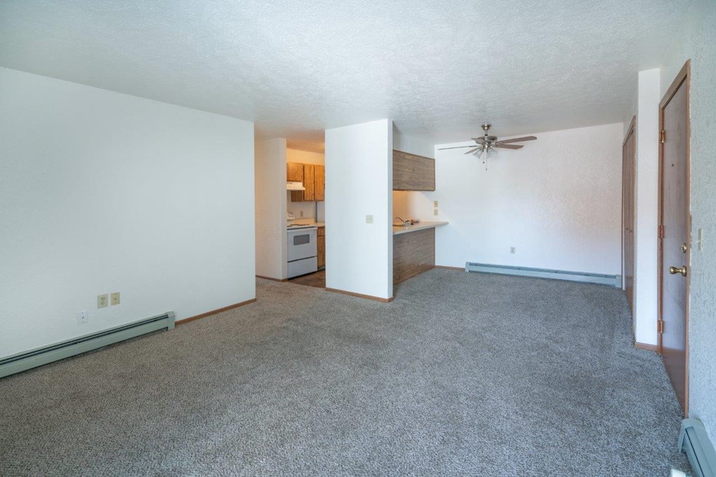 an empty living room and kitchen with a ceiling fan