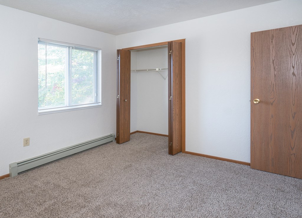 an empty bedroom with a closet and a window