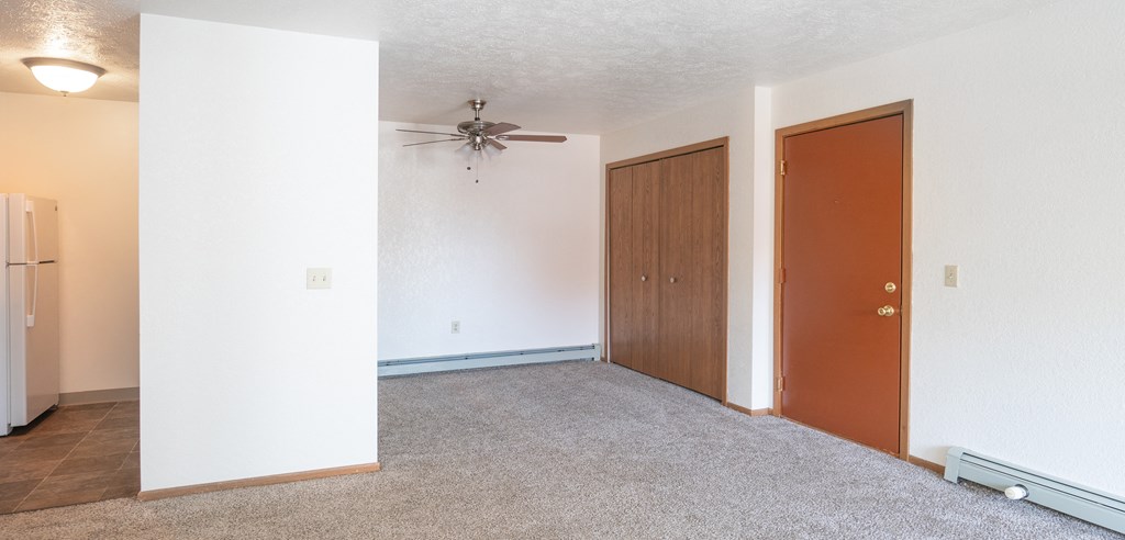 an empty room with a ceiling fan and two doors