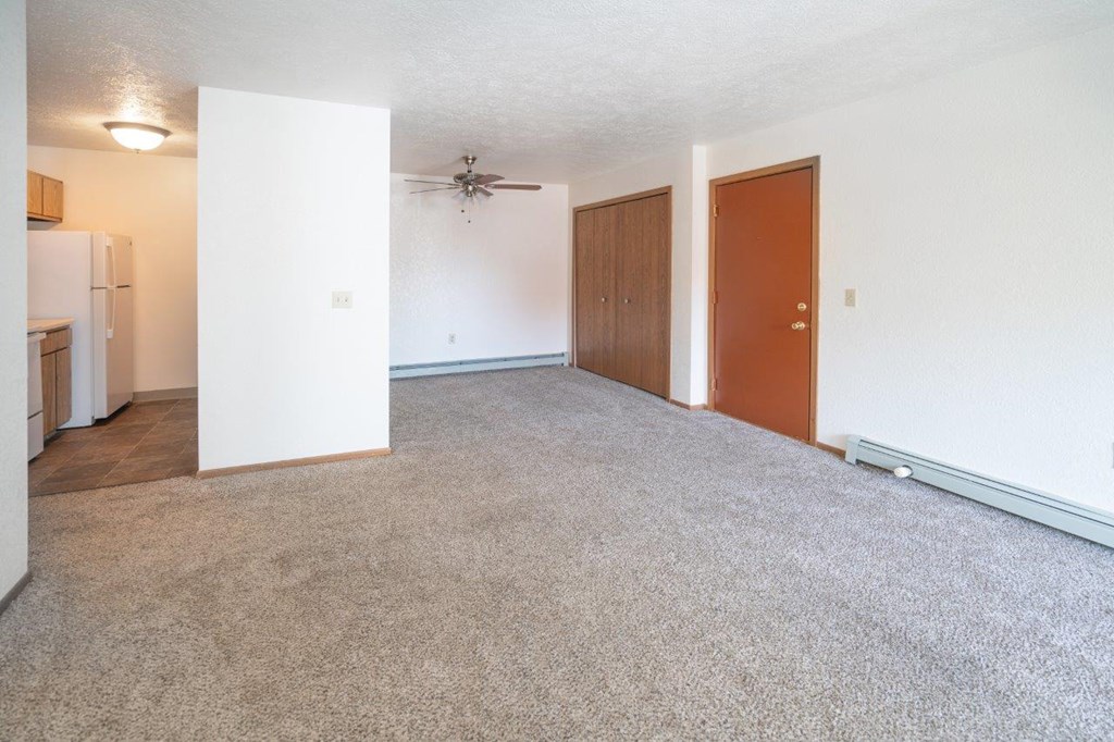 an empty living room with white walls and a ceiling fan