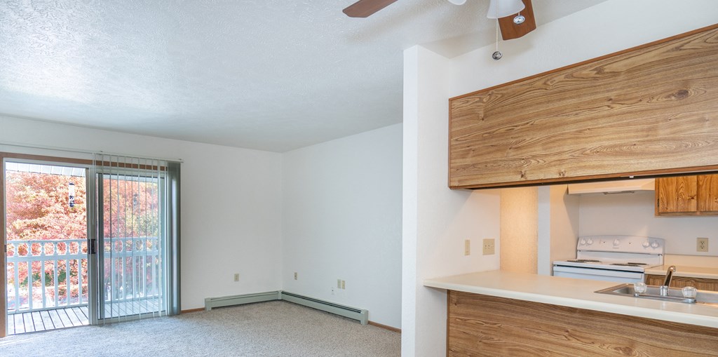 a kitchen and living room with a sliding glass door to a balcony