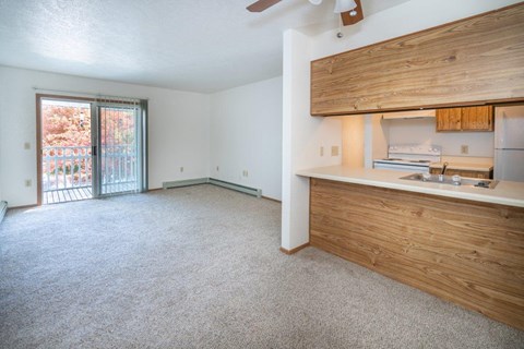 an empty living room with a kitchen and a sliding glass door