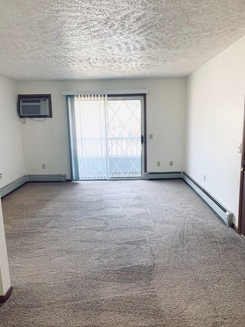 an empty living room with a door to a balcony