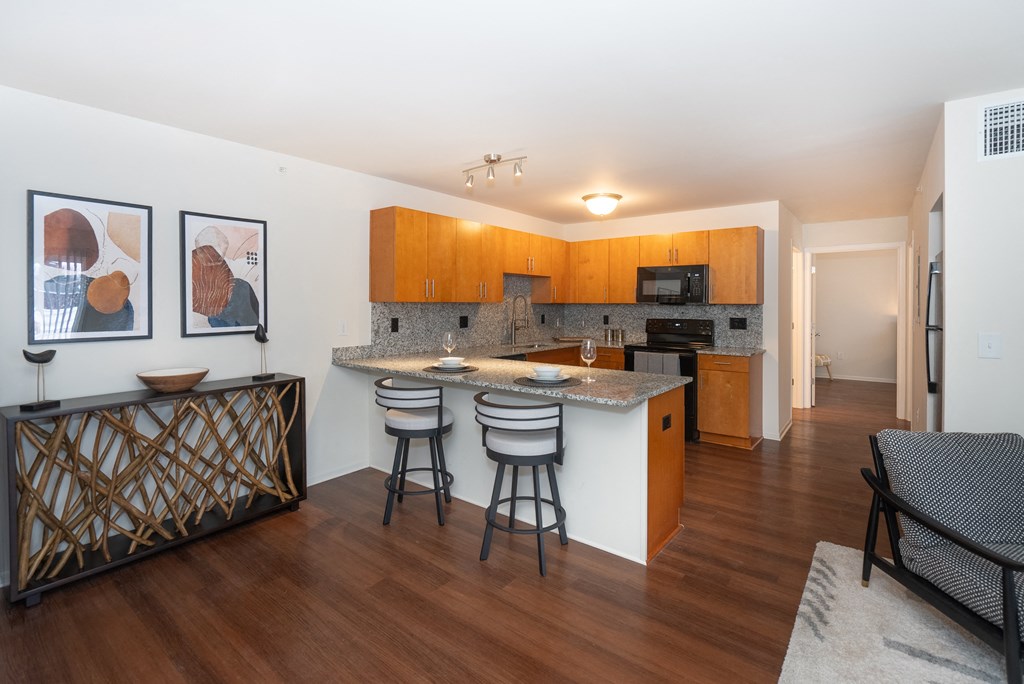 A kitchen with a bar and chairs.