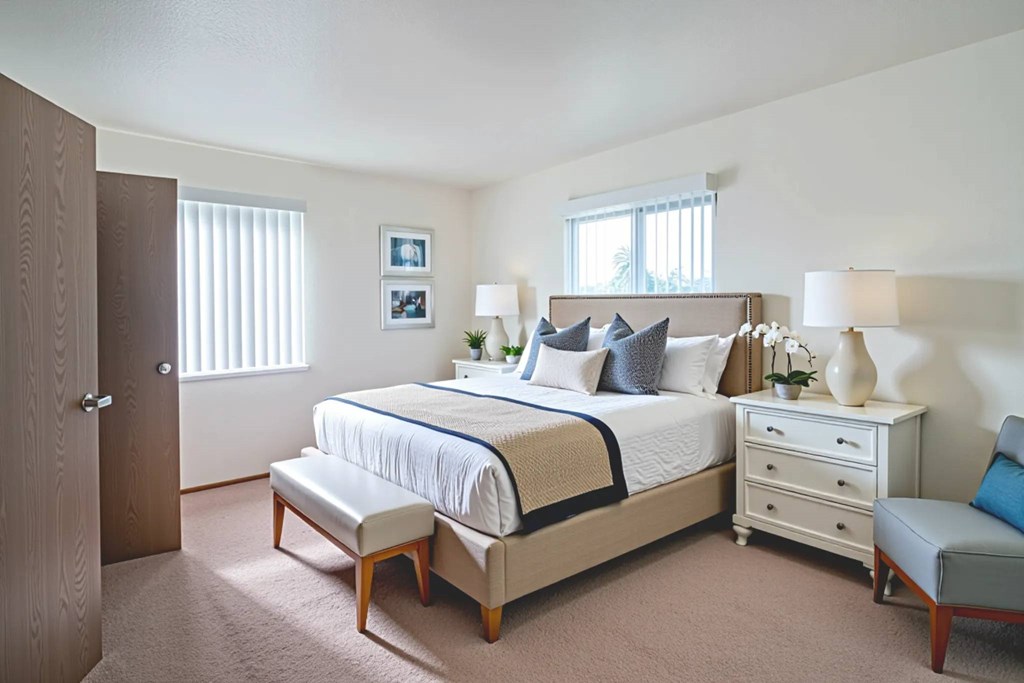 A bedroom with a bed, nightstand, and chair.