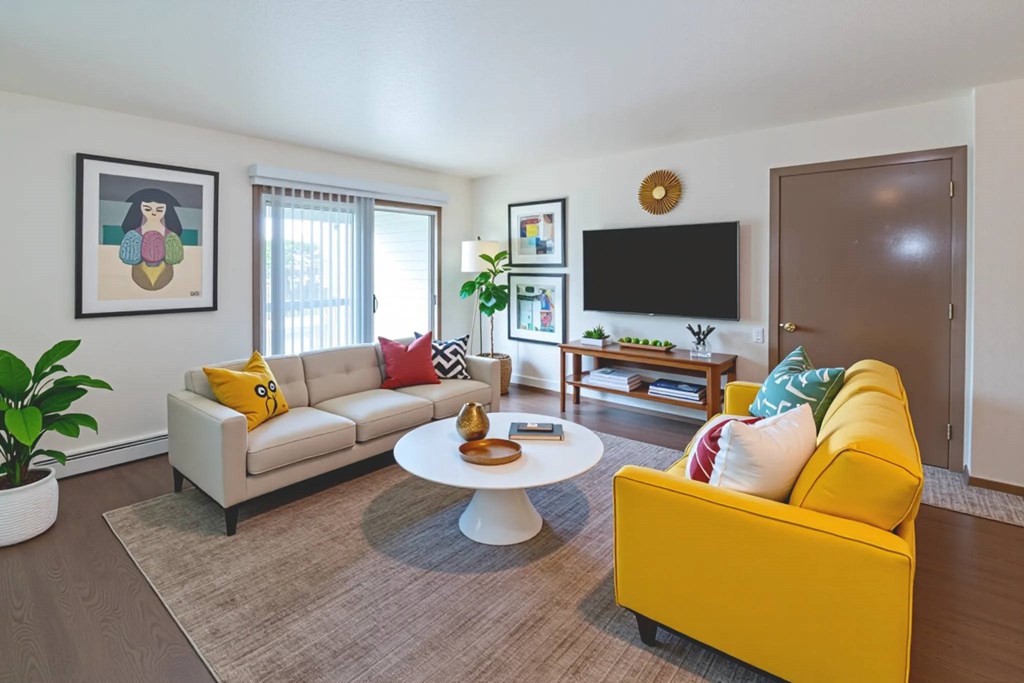 A living room with a yellow couch and a white coffee table.