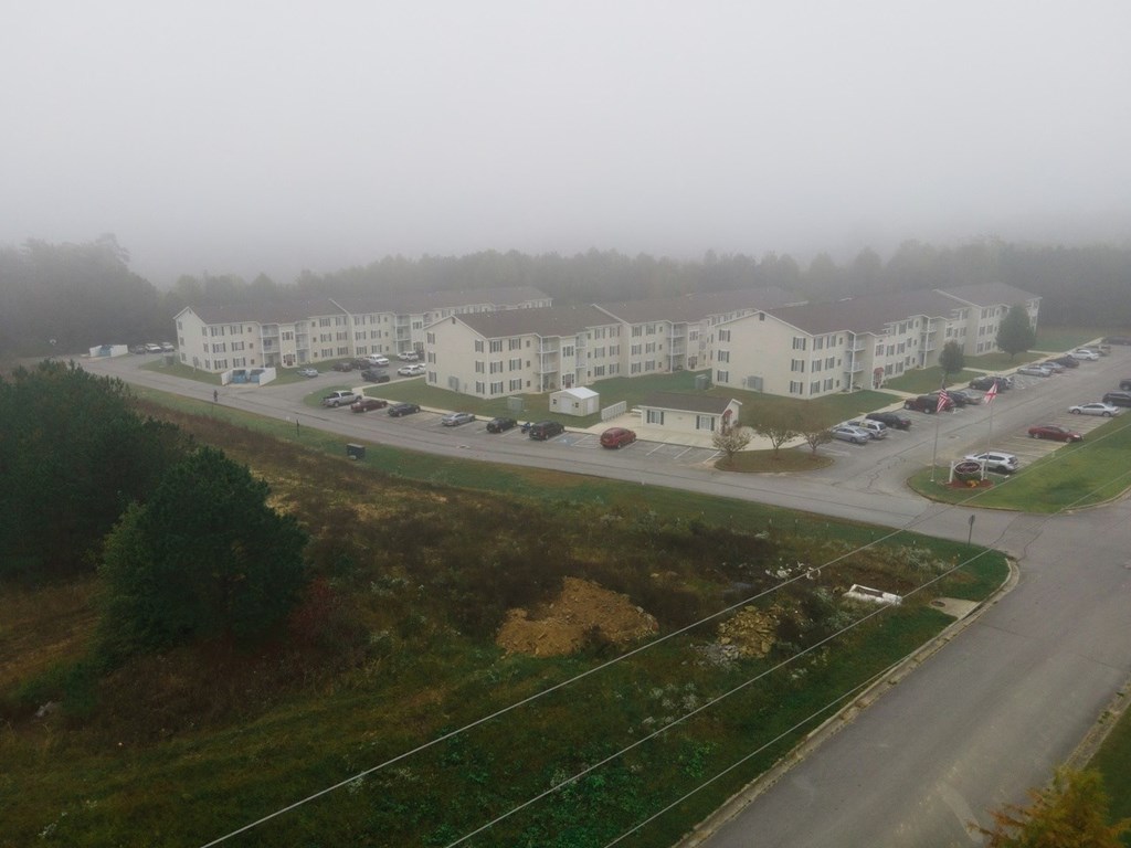 a foggy view of an apartment complex with a road and parking lot
