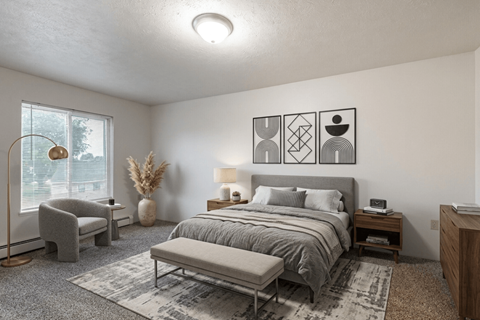 A bedroom with a large bed and a grey chair.