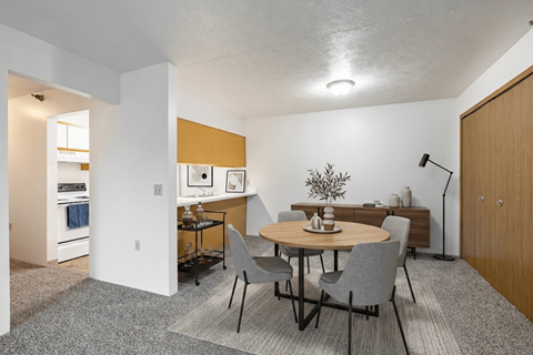 A dining room with a round table and grey chairs.