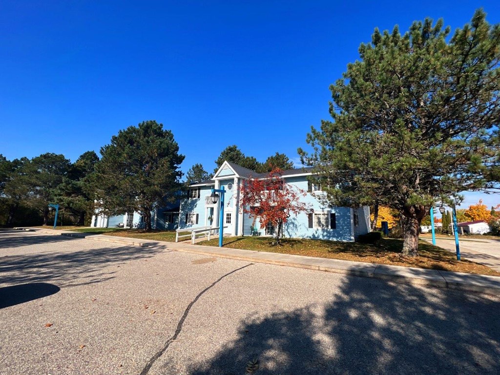 a white house with trees and a street in front of it