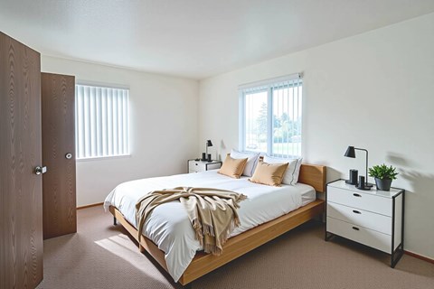 A bedroom with a bed, nightstand, and window.