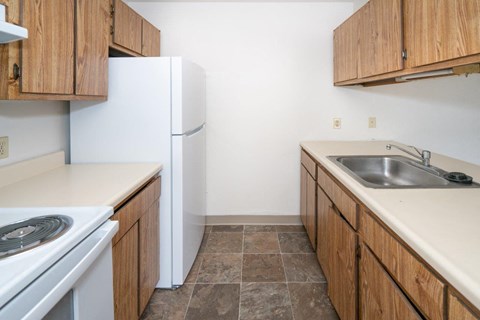 A kitchen with a white fridge and wooden cabinets.