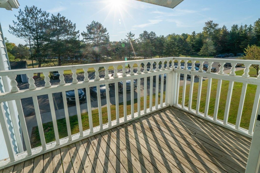 a balcony with a view of a yard and the sun shining on it
