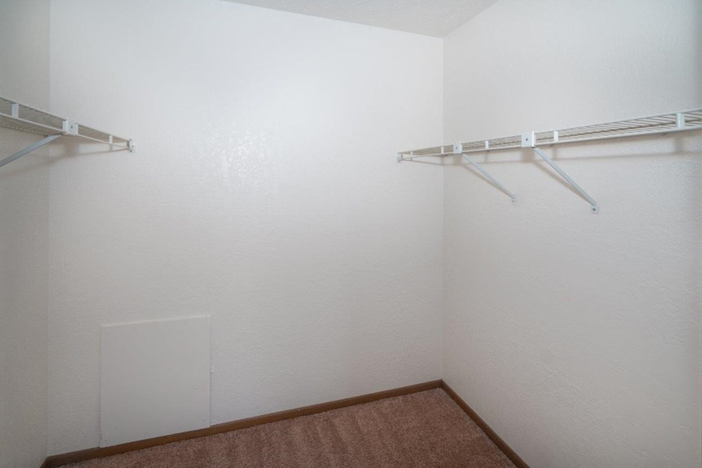 a white closet with two hanging racks on the wall