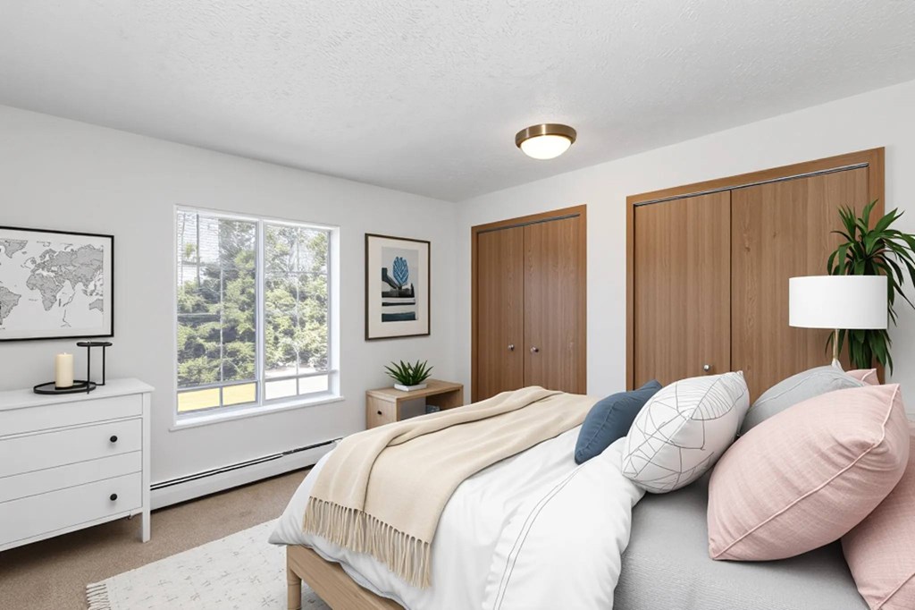 A bedroom with a bed, nightstand, and a plant.