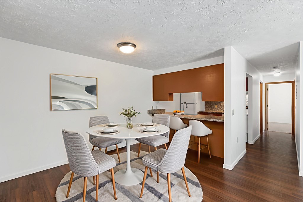 A dining room with a white table and grey chairs.