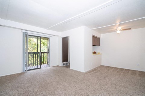 an empty living room with a sliding glass door to a balcony