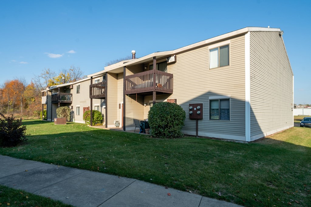 a yellow apartment building with a balcony and a sidewalk