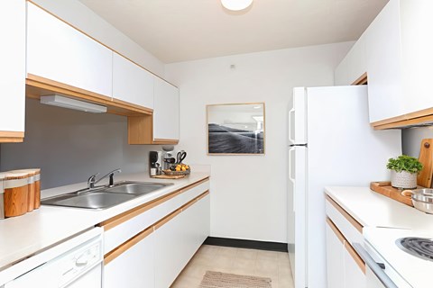 A kitchen with white cabinets and a white fridge.