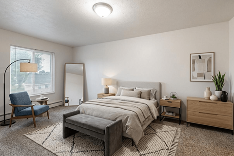 A well-lit bedroom with a large bed, a chair, and a nightstand.