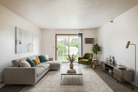A living room with a grey couch, a green armchair, a coffee table, and a large window.