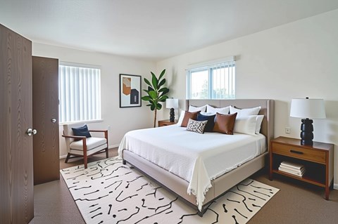 A bedroom with a large bed and a wooden nightstand.