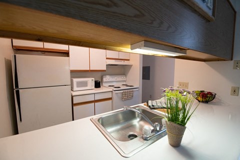 A kitchen with a white counter top and a white sink.