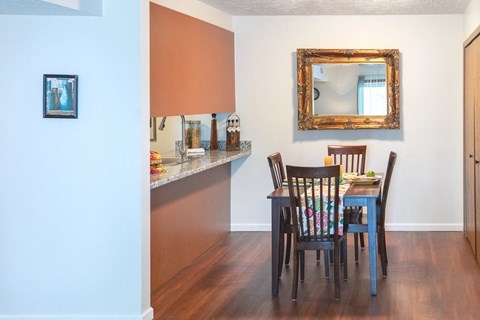 a dining room with a table and chairs and a kitchen with a counter