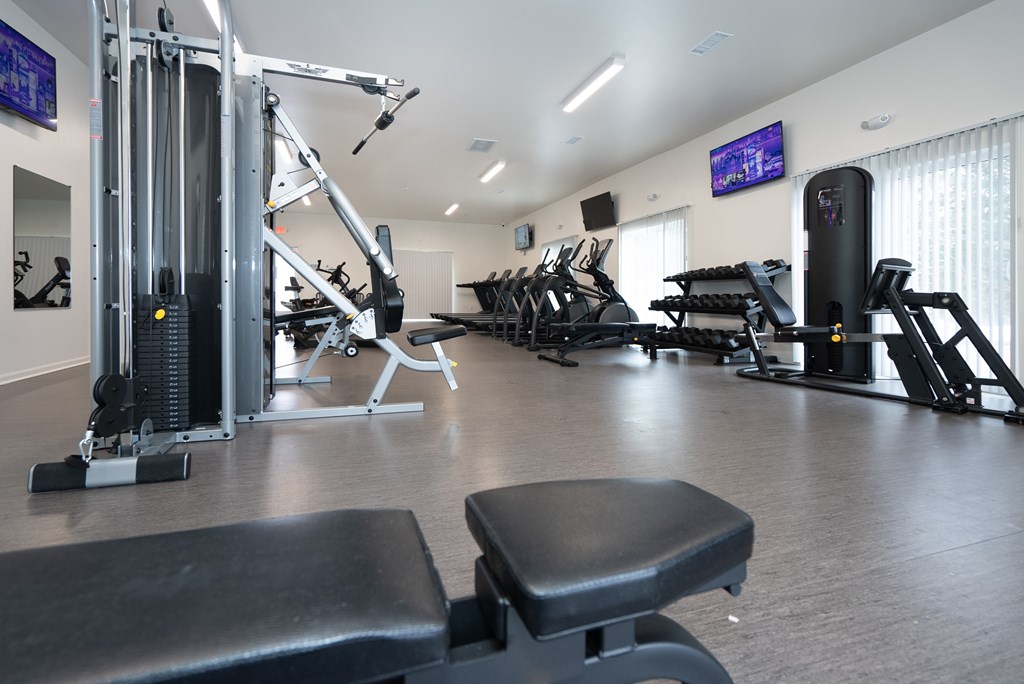 A gym with a variety of equipment including treadmills, weights, and exercise machines.