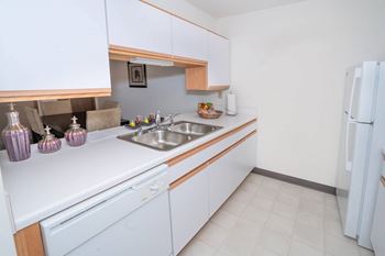 A kitchen with white cabinets and a white fridge.