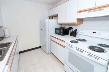 A white kitchen with a stove, refrigerator, microwave, and toaster.