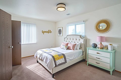 A bedroom with a bed, nightstand, and a mirror on the wall.