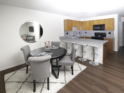 A modern kitchen with a round table and grey chairs.