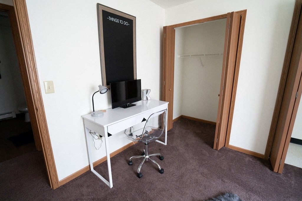 a room with a white desk and a mirror and a closet