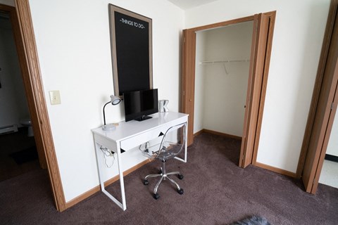 a room with a white desk and a mirror and a closet