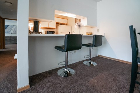 a bar with two stools in front of a kitchen