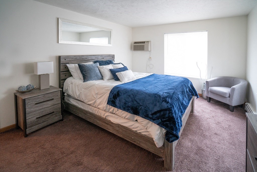 a bedroom with a bed and a chair and a window