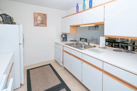 A kitchen with white cabinets and a black mat on the floor.