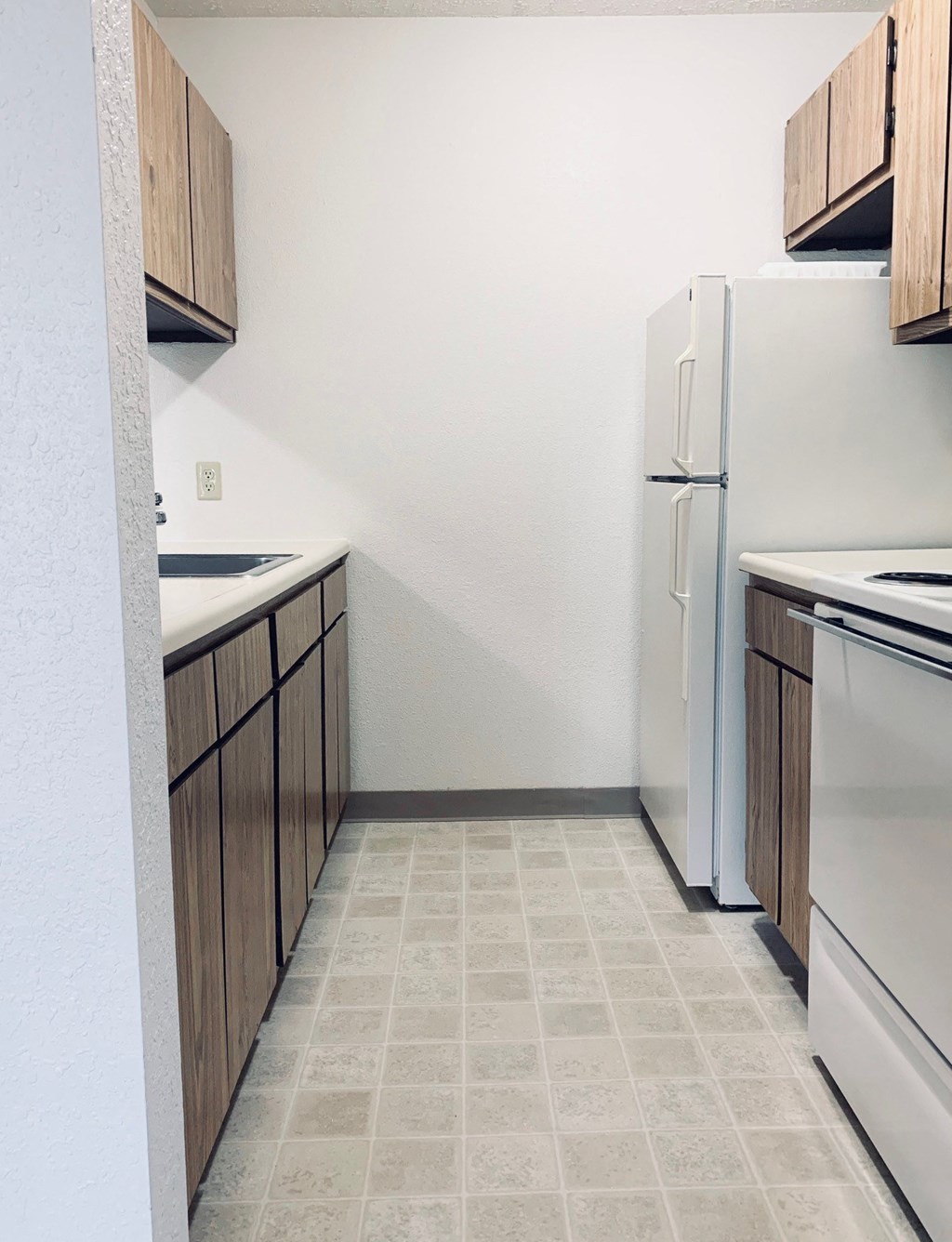 an empty kitchen with white appliances and wooden cabinets