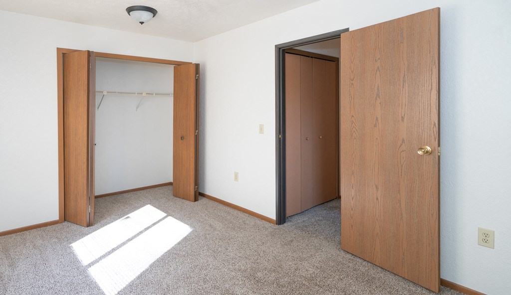 an empty room with two doors and a closet