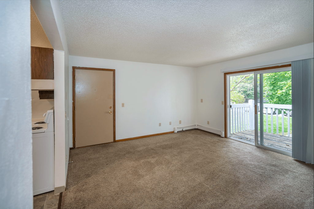 an empty living room with a sliding glass door to a patio