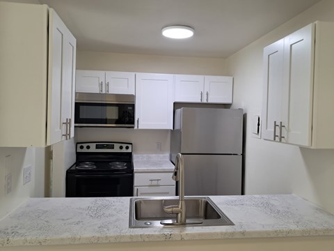 A kitchen with a stove, oven, microwave, and refrigerator.