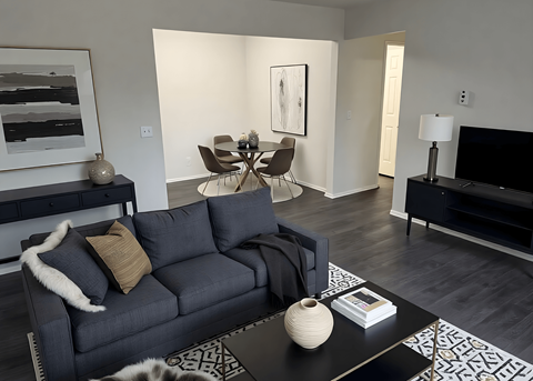 A living room with a grey couch, a coffee table, and a painting on the wall.