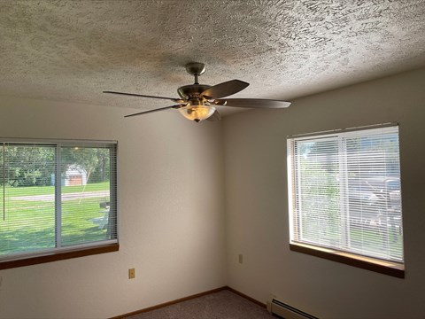 a living room with a ceiling fan and two windows